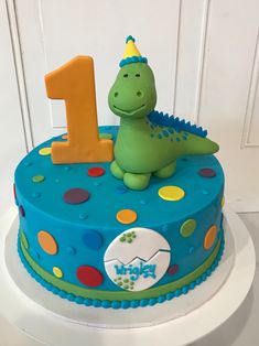 a birthday cake decorated with a dinosaur and the number one on it's side