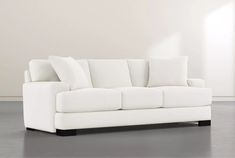 a white couch sitting on top of a gray floor next to a wall and window