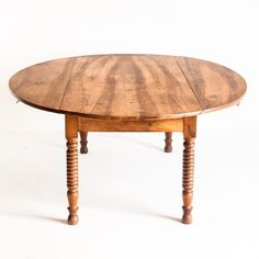 an oval wooden table with turned legs on a white background is seen in this image