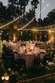 an outdoor dining area with tables, chairs and string lights strung over the top of them