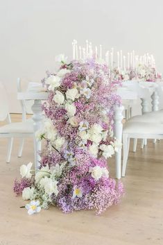 a bunch of flowers sitting on top of a wooden floor next to a white table