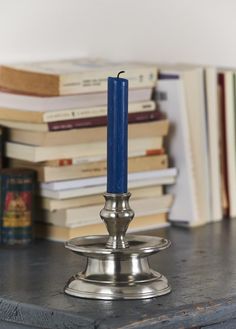 a silver candle holder sitting on top of a table next to books and a stack of books