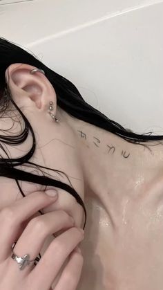 a woman with black hair and piercings laying in a bathtub holding her hand up to her ear