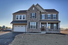 a two story house in the middle of an empty lot with gravel and grass around it