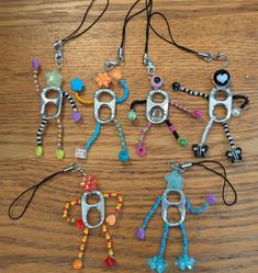 six different key chains with bead designs on them sitting on a wooden table top