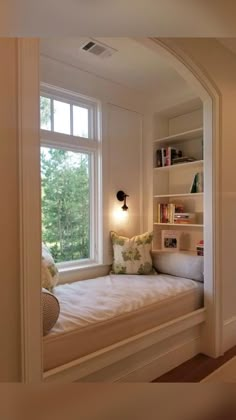 there is a window seat in the corner of this room with bookshelves on either side