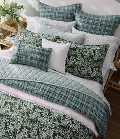 a bed covered in green and white floral comforters