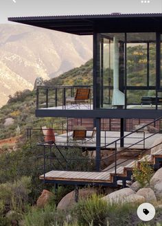 a house on the side of a mountain with stairs leading up to it's upper level