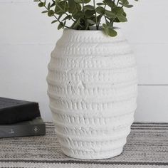 a white vase sitting on top of a table next to a black and white book