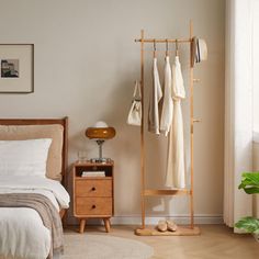 a bed room with a neatly made bed and a wooden coat rack on the wall