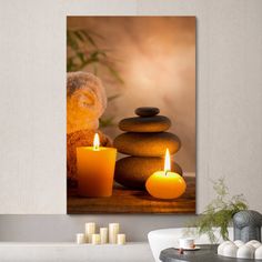 two candles are lit in front of some rocks on the table and one candle is next to it