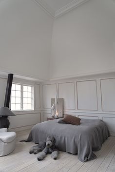 a bedroom with white walls and wood flooring has a large bed in the middle