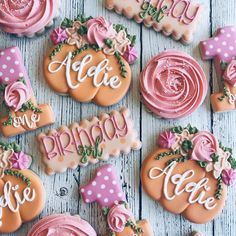 decorated cookies are arranged on a white table with pink and orange decorations, such as roses