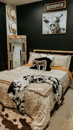 a bed room with a neatly made bed and cow decor on the wall above it