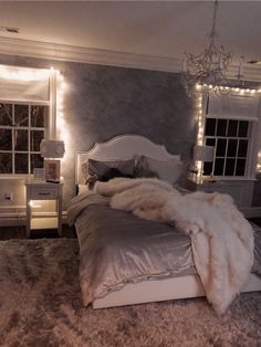 a white bed sitting in a bedroom next to a window with lights on the walls