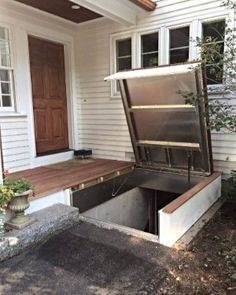 an open door on the side of a white house with a wooden deck in front of it