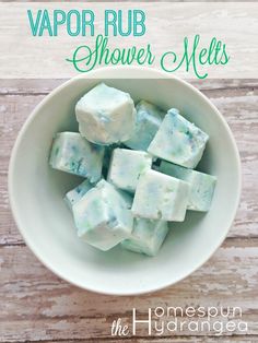 a white bowl filled with lots of different types of soap cubes on top of a wooden table