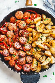 a skillet filled with potatoes and sausages, garnished with parsley