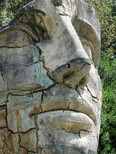 a carved stone face in front of some trees