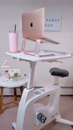 a white desk with a laptop on it and a pink cup sitting next to it