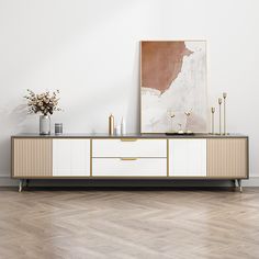 a white and gold sideboard with vases on it next to a painting in an empty room