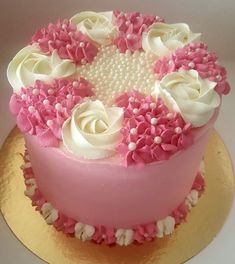 a pink and white cake with flowers on it sitting on a gold plated platter