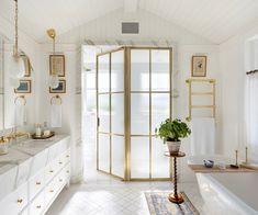 a bathroom with white walls and gold trimmings on the doors, windows, and bathtub