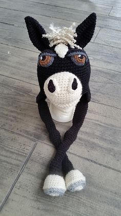 a crocheted black and white horse head sitting on top of a wooden floor