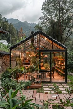 a small greenhouse in the middle of a garden with lots of greenery and plants