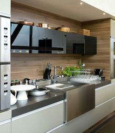 a modern kitchen with stainless steel appliances and wood paneling on the wall behind the sink