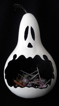 a white and black halloween decoration with candy in the shape of a ghost, on a black background