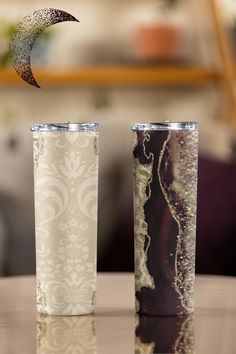 two tumblers sitting on top of a table next to each other with a half moon in the middle