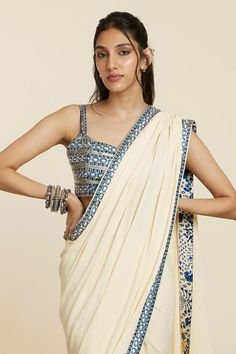 Beige pre-draped saree with geometric embroidered border. Paired with a blouse with all over abstract geometric embroidery.
Components: 2
Pattern: Embroidery
Type Of Work: Geometric, Abstract
Neckline: Square Neck
Sleeve Type: Sleeveless
Fabric: Crepe
Color: Beige
Other Details: 
Asymmetric drape detailing on saree
Occasion: Sangeet - Aza Fashions Traditional Sleeveless Pre-draped Saree With Mirror Work, Summer Reception Pre-draped Saree, Traditional Drape Saree With Mirror Work For Summer, Traditional Sleeveless Pre-draped Saree For Navratri, Navratri Draped Blouse Piece With Mirror Work, Draped Blouse Piece With Mirror Work For Navratri, Designer Wear Pre-draped Saree For Summer, Sleeveless Georgette Pre-draped Saree For Navratri, Designer Pre-draped Saree For Summer