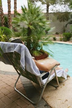 a woman sitting in a chair next to a pool with a towel over her head