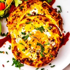 two frittatas on a plate with ketchup and avocado