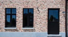 a brick building with three black windows and a fire hydrant in front of it