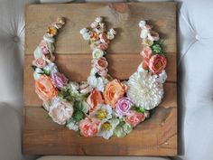 a wooden sign with flowers on it sitting on a couch next to a pillow and chair