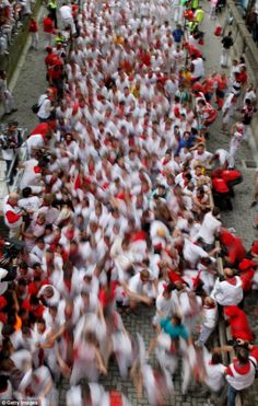 a large group of people in white and red shirts are walking down the street together