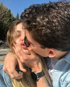 a man and woman kissing each other while wearing sunglasses