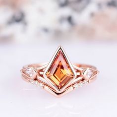 a close up view of a ring with an orange and white diamond in the center