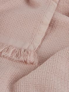 a pink blanket with fringes on it