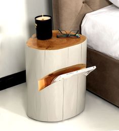 a wooden table with a magazine holder and glasses on it next to a white bed