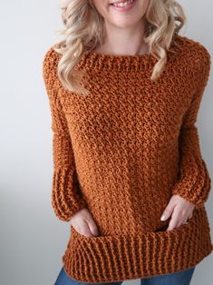 a woman is wearing an orange sweater and smiling at the camera with her hands in her pockets