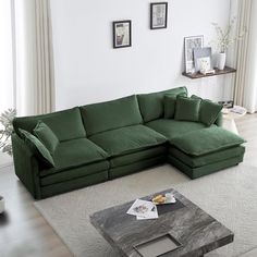 a living room with a large green couch and coffee table in front of the window