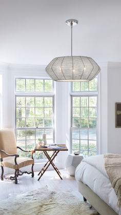 a bed room with a neatly made bed and two chairs next to a table in front of large windows