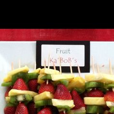 fruit kabobs with kiwi and strawberries are arranged on a white plate