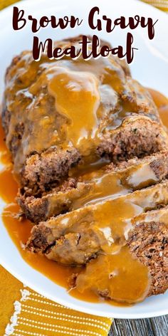 a plate topped with meatloaf covered in gravy on top of a table