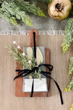 a cutting board and knife on top of a table next to some christmas tree branches