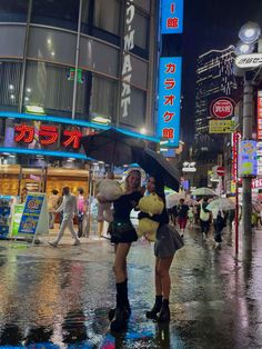 two women are standing in the rain with an umbrella and teddy bear on a city street