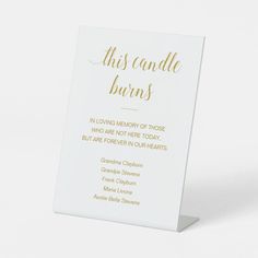 a white card with gold foil lettering that reads, this candle burns in loving memory of those who are not there today but two people in our hearts